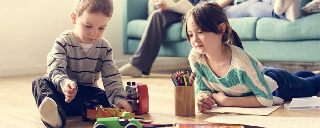 Kinderzuschlag - Kinder spielen auf Boden vor Sofa mit Eltern